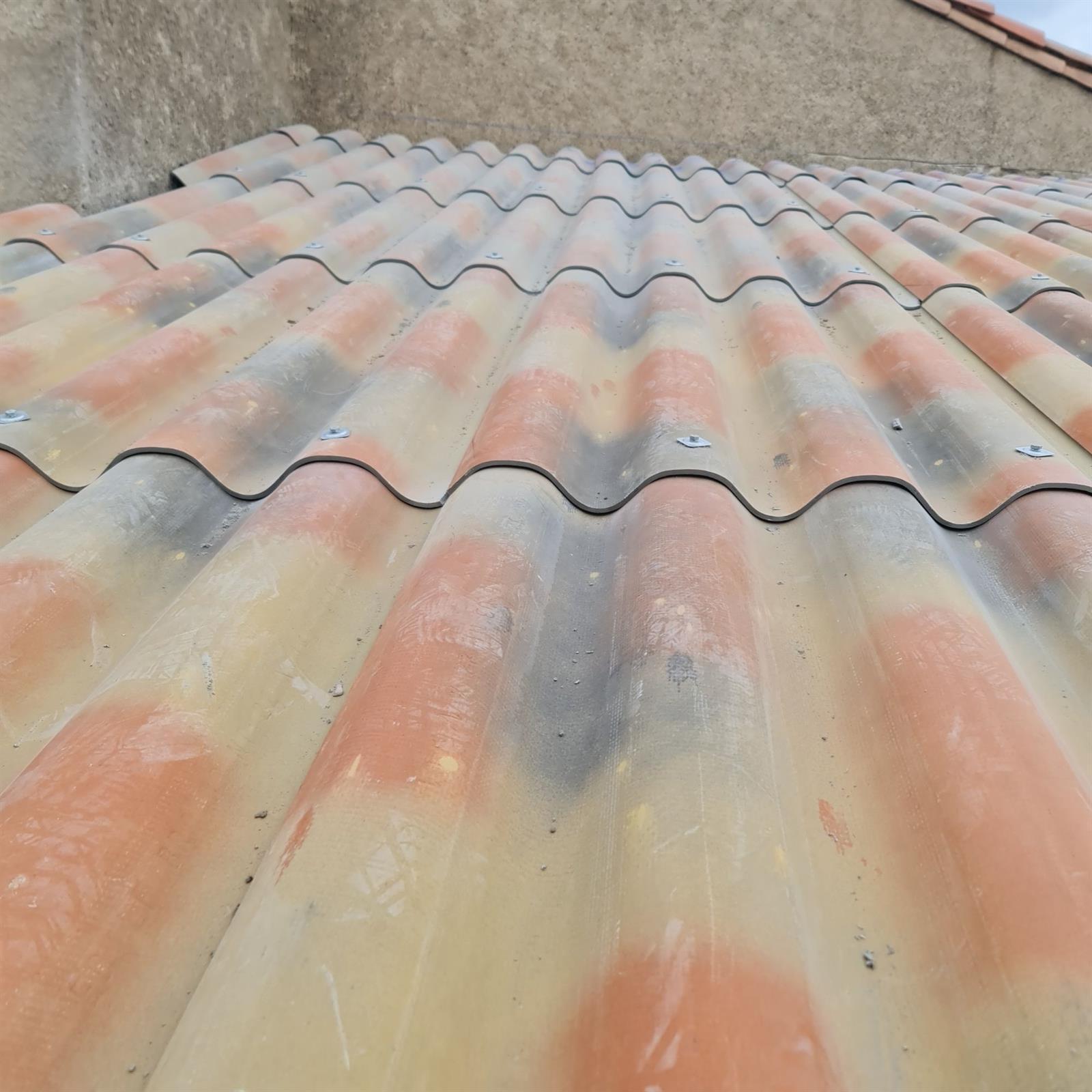 Couverture en plaques ondulées vissées, vue de dessus le long d'un mur en béton, chantier MCI Construction dans l'Aude