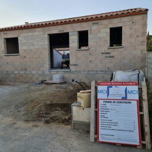 Élévation en parpaings avec le panneau de permis de construire MCI Construction affiché sur le chantier