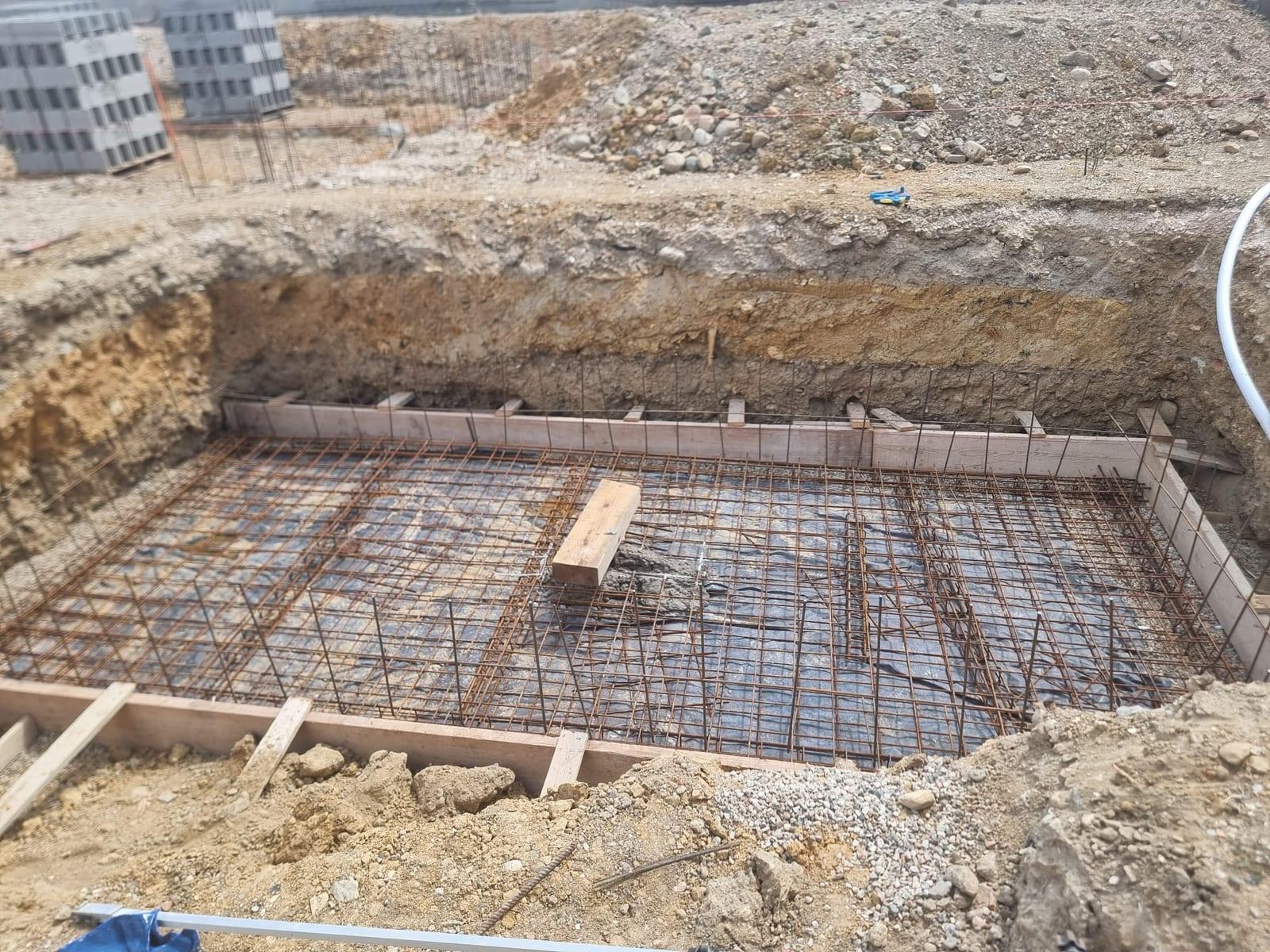 Fond d'une piscine coffré en bois et ferraillé en double nappe, avec les aciers en attente dressés en périphérie, avant coulage du béton